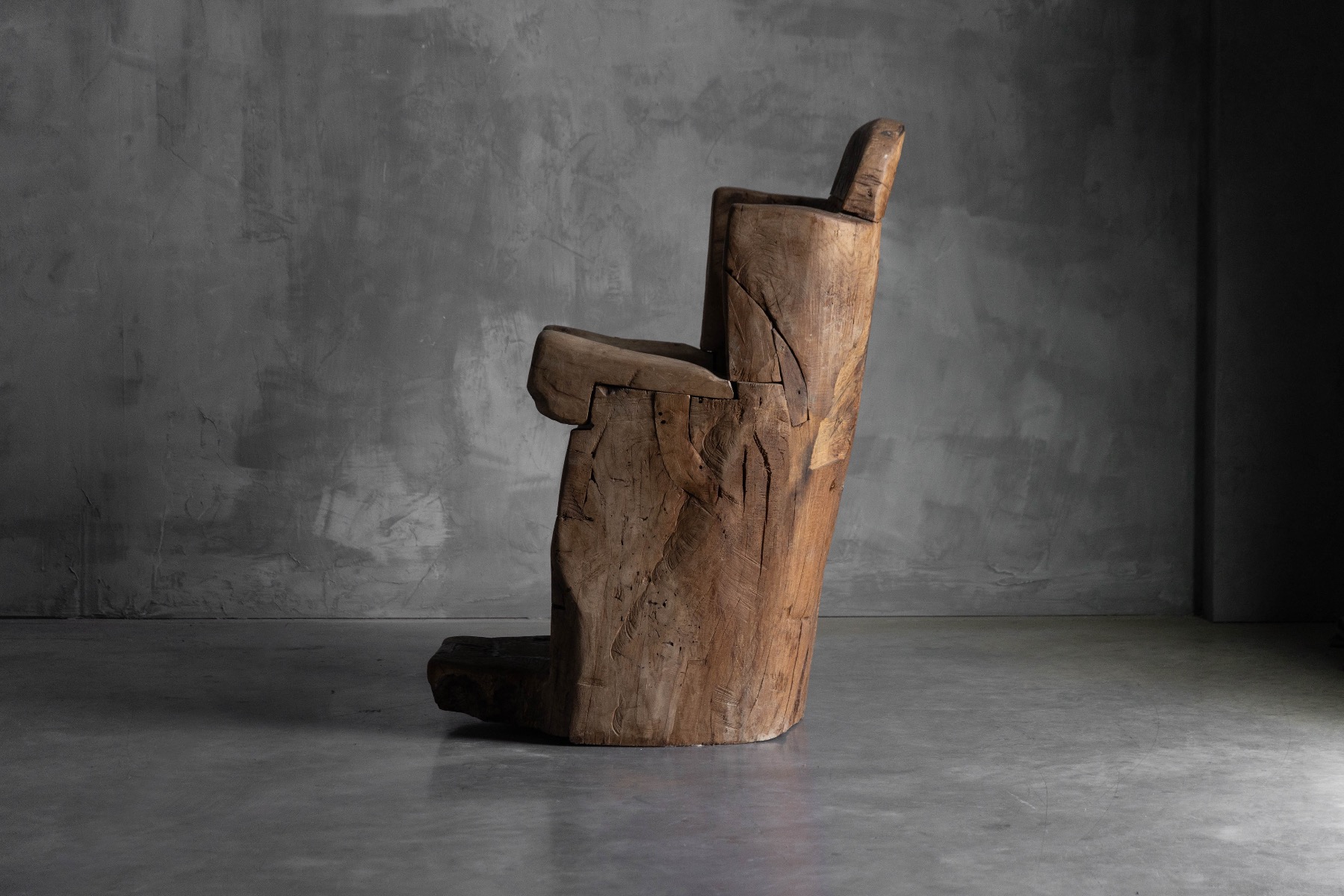 Sculptural monoxylite throne chair with archaic presence