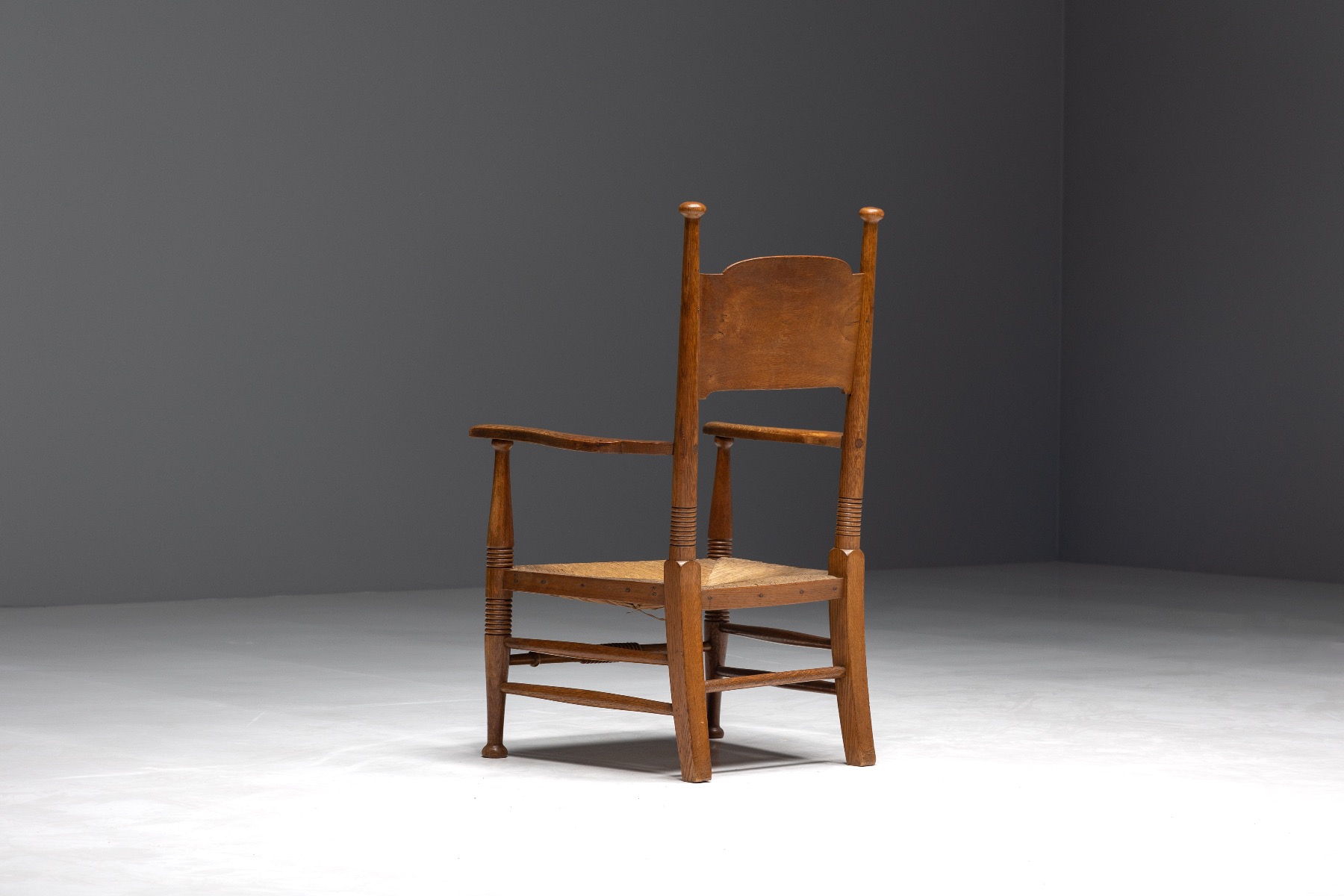Antique rustic oak armchair with straw seat